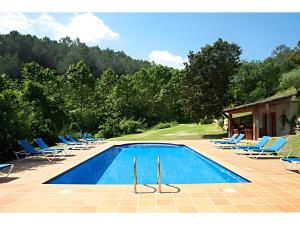 ein Schwimmbad mit Stühlen und einer Gruppe in der Unterkunft Can Tapis in Santa María de Camós