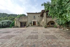 ein großes Steinhaus mit einer großen Auffahrt in der Unterkunft Can Tapis in Santa María de Camós