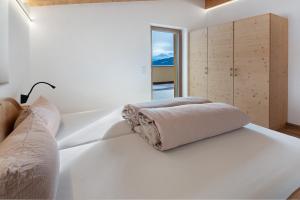 a white bedroom with a bed and a window at Hof Am Egg in Malles Venosta