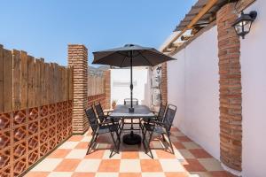 a patio with a table and chairs and an umbrella at Casa Rústica in Vélez de Benaudalla