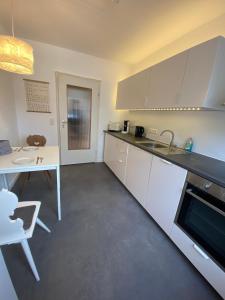 a kitchen with white cabinets and a table and a sink at Lichtblick unter der Buche in Titisee-Neustadt