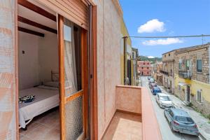 a balcony with a bed and a view of a street at Casa rustica in Gonnesa