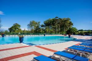 a large swimming pool with blue chairs and trees at Côte Basque in Urrugne