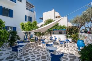 a patio with blue chairs and tables in front of a building at Livadia Seaside Studios 6 in Parikia