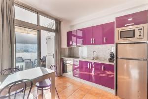a kitchen with purple cabinets and a table with chairs at Vv Velero in Puerto de Mogán