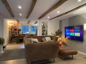 a living room with a couch and a flat screen tv at Sauerland Apartments Willingen in Willingen
