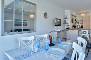 a dining room with a glass table and white chairs at Maison Les Flots De Port-mer in Cancale +15 photos