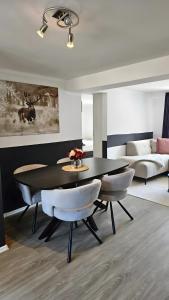 a dining room with a table and chairs and a couch at Sauerland Apartments Willingen in Willingen