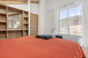 a bedroom with an orange bed and a bath tub at La Master Grange De Queyran in La Palud-sur-Verdon