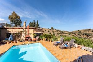 a swimming pool with two chairs and a house at Cosy house jacuzzi wifi pool view in Mijas