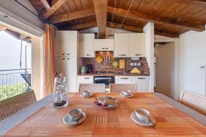 a kitchen and dining room with a wooden table at Splendido loft panoramico in Veleso +8 photos