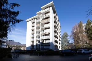 a white apartment building with cars parked in a parking lot at Studio Montcalm in Aix-les-Bains