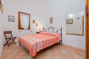 a bedroom with a bed and a chair and a mirror at Domus Dejana in San Teodoro