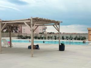 a person laying under a pergola next to a swimming pool at Chez Colette d'en bas in Le Barcarès