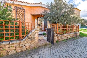 a house with a gate and a stone fence at Domus Dejana in San Teodoro