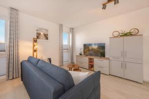 a living room with a blue couch and a tv at FeWo Meerzeit Bernsteinquartier in Loddin