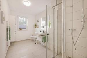 a bathroom with a shower and a toilet and a sink at FeWo Meerzeit Bernsteinquartier in Loddin +25 photos