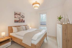 a bedroom with a bed with white sheets and a window at FeWo Meerzeit Bernsteinquartier in Loddin