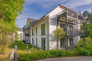 a large white house with balconies and trees at FeWo Meerzeit Bernsteinquartier in Loddin