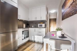 a kitchen with white cabinets and a stainless steel refrigerator at Sea and Sunset Love in San Marcos