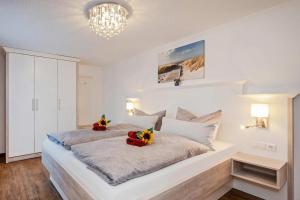 a white bedroom with a large bed with flowers on it at Bungalow "Giny" in Bansin