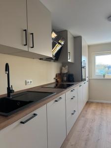 a kitchen with white cabinets and a sink and a window at Apartment Oben in der Heide in Faßberg