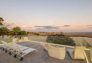 a patio with white chairs and a view of the beach at Seafront villa with jacuzzi in Maspalomas