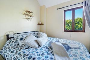 a bedroom with a blue and white bed with a window at Gîte Chemin Des Hêtres in Armaillé