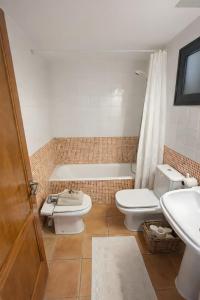 a bathroom with a toilet and a sink and a tub at Duplex Laura in Es Mercadal +16 photos