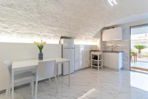 a white kitchen with a white table and chairs at La Porta Sul Mare- Timone in Mola di Bari