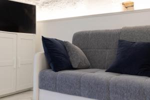a gray couch with blue pillows in a living room at La Porta Sul Mare- Timone in Mola di Bari