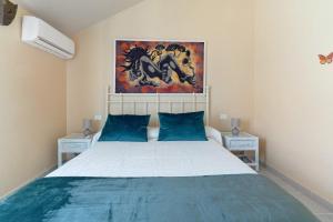 a bedroom with a bed with blue pillows and a painting at Colina Verde Maspalomas in Maspalomas