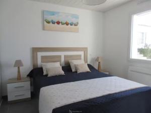 a bedroom with a bed with blue sheets and a window at La Maison Du Marché - Balcon in La Tranche-sur-Mer