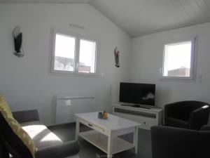 a white living room with a tv and a table at La Maison Du Marché - Balcon in La Tranche-sur-Mer