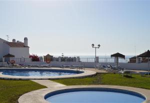 a swimming pool with tables and chairs and the ocean at Townhouse with Sea View in Nerja