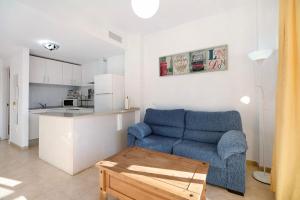 a living room with a blue couch and a kitchen at Apartamento Merce in Rota