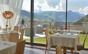 a restaurant with two tables and a view of mountains at Hotel Fanes in Selva di Val Gardena