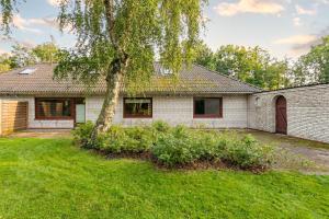 a white brick house with a tree in the yard at De Maade in Enge-Sande