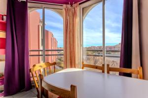 a table and chairs in front of a large window at Chez Colette du haut in Le Barcarès