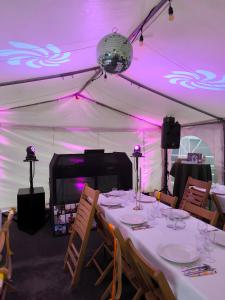 a dining table in a tent with purple lights at Domaine Baraque in Pouillon