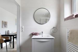 a white bathroom with a sink and a mirror at Ferienwohnung Emilia 2 in Garding +18 photos