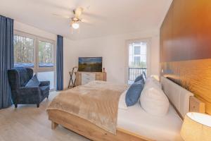 a bedroom with a large bed and a chair at FeWo Lieblingsort in Loddin