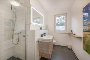 a white bathroom with a sink and a shower at FeWo Lieblingsort in Loddin +26 photos