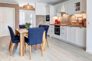 a kitchen with a wooden table and blue chairs at FeWo Am Pier 7a in Loddin