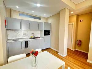 a kitchen with white cabinets and a table with flowers on it at Setubal Prime, By Home Match in Setúbal