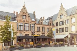 a building with tables and umbrellas in front of it at Guesthouse Amfora in Poperinge