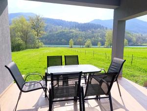 a table and chairs on a porch with a view of a field at Kucica na Drini MINJA in Višegrad
