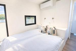 a white bedroom with a bed and a window at Floatinghouse Bakerman in Zehdenick