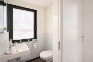 a bathroom with a toilet and a sink and a window at Floatinghouse Bakerman in Zehdenick