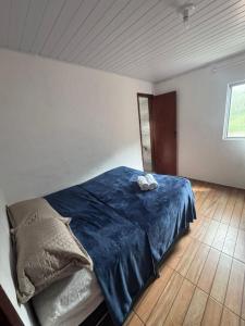 a bedroom with a bed with blue sheets and a window at Família Ebeneze in Santa Maria Madalena +4 photos